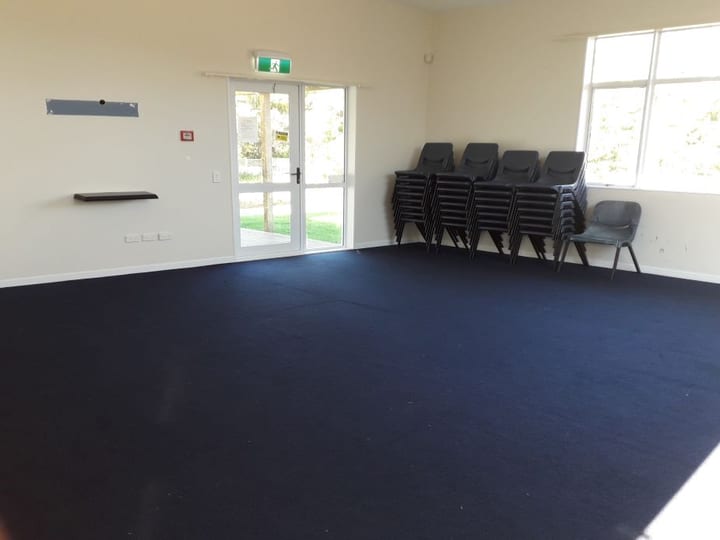 Empty room with dark carpet and stacked chairs by window