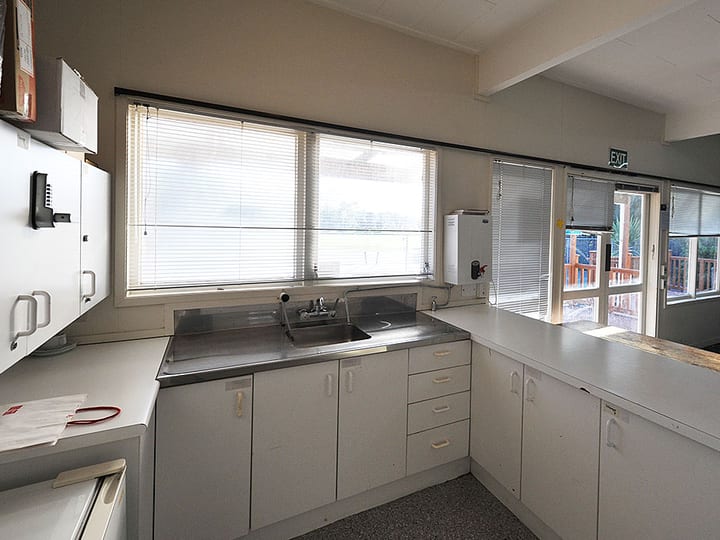 Plain kitchen with sink, bench, and windows overlooking deck