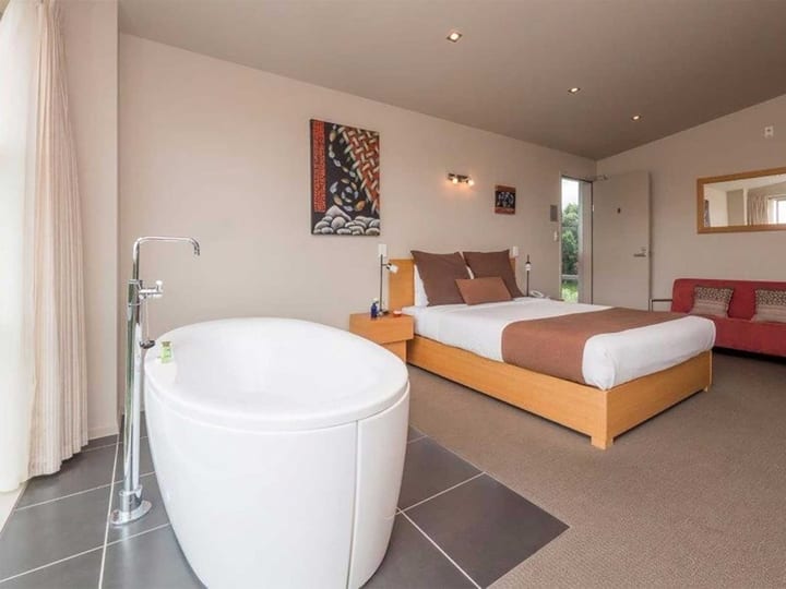 Suite with a freestanding bath, king bed and garden outlook through sliding doors