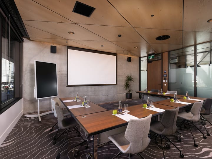 Meeting room with U-shaped table layout, projection screen and glazed walls