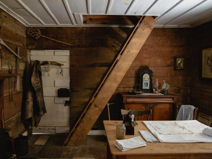 Rustic period room interior with timber walls, wooden furniture and antique clock