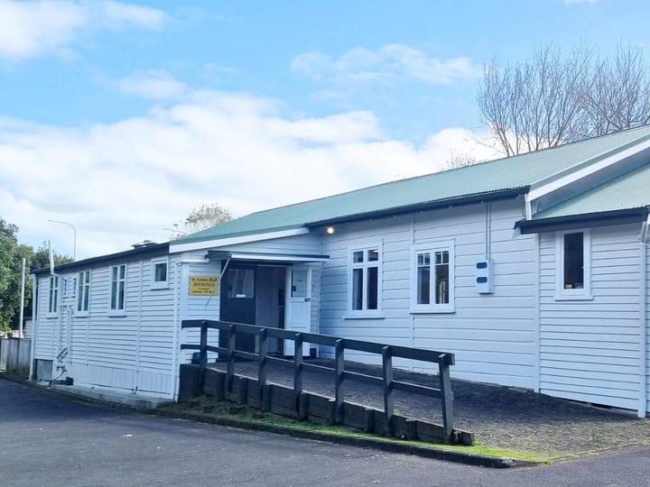 White weatherboard community hall exterior with green roof