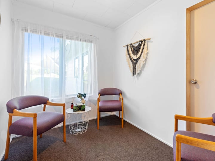 Small room with three armchairs, a side table, and a wall hanging decoration