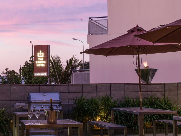 Rooftop terrace at dusk with timber tables, market umbrella, gas torch, garden strip