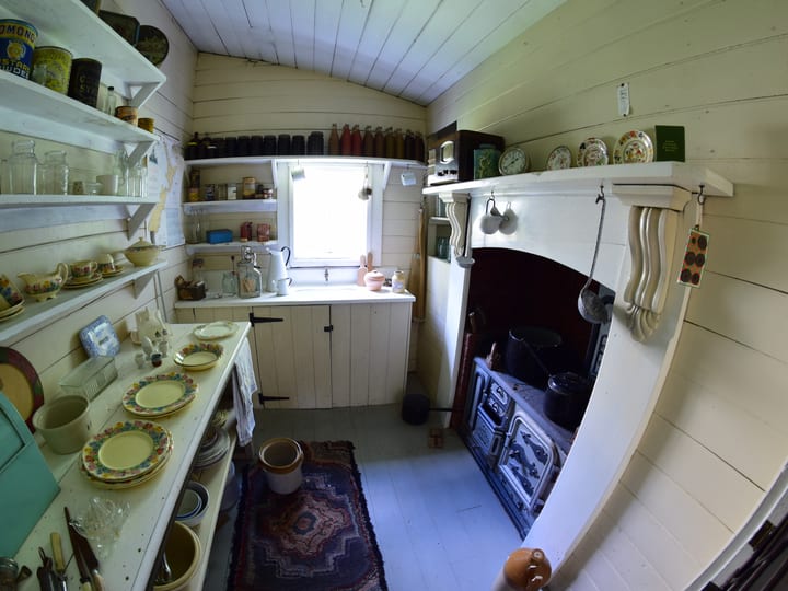 Heritage kitchen with open shelving, cast iron range, and period crockery and utensils on display