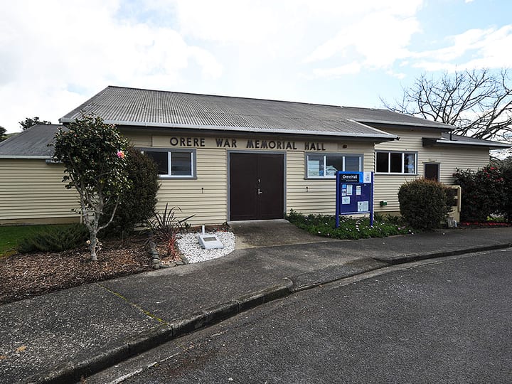 Single-storey weatherboard hall with corrugated roof and entrance garden