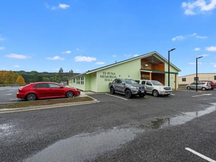 Side view of light green memorial hall with carpark and cars