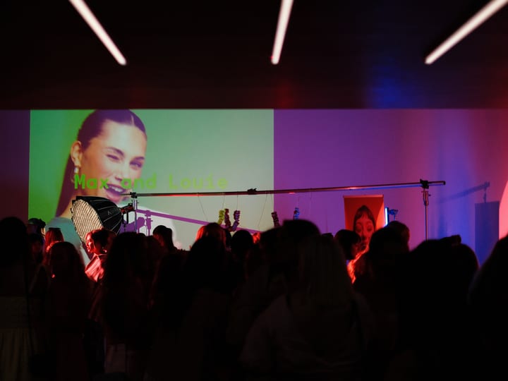 Event space with coloured projection lighting, screen, crowd, and microphone stand
