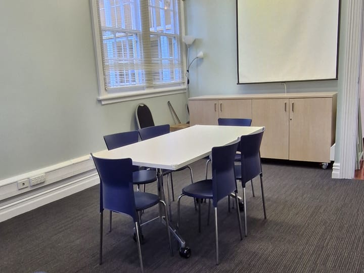 Small meeting room with table, chairs and projection screen