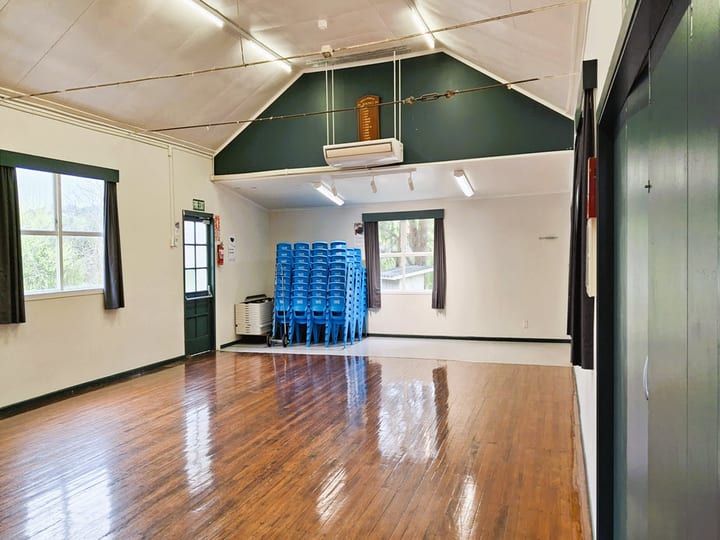 Hall interior with timber floor, vaulted ceiling and stacked blue chairs