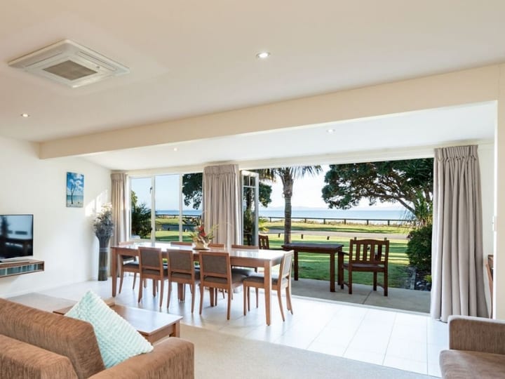 Open-plan suite lounge and dining area with sliding doors to lawn and sea views