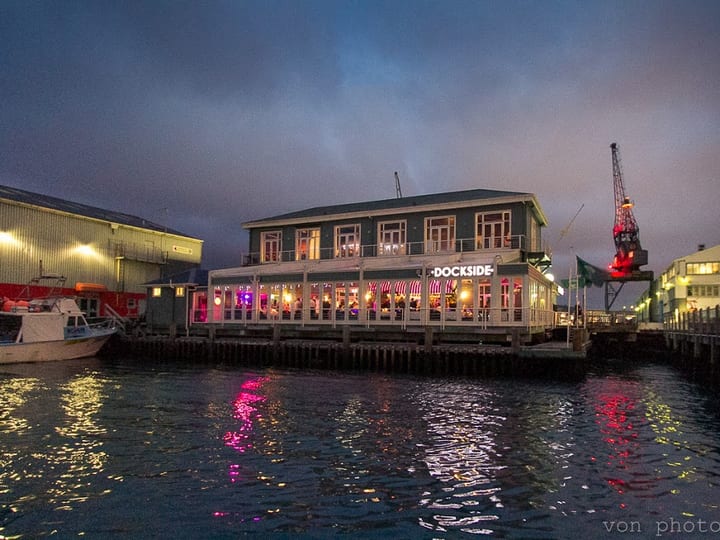 Dockside restaurant at night from the water, lit facade with reflections