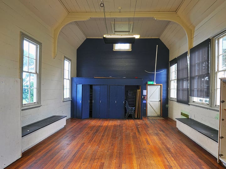Hall interior with arched timber ceiling, polished timber floor, and raised platform