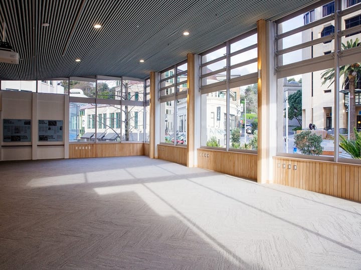 Bright open hall with floor-to-ceiling glazing, timber linings and city views