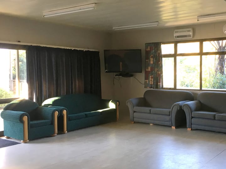 Casual lounge room with couches, television and large windows to gardens