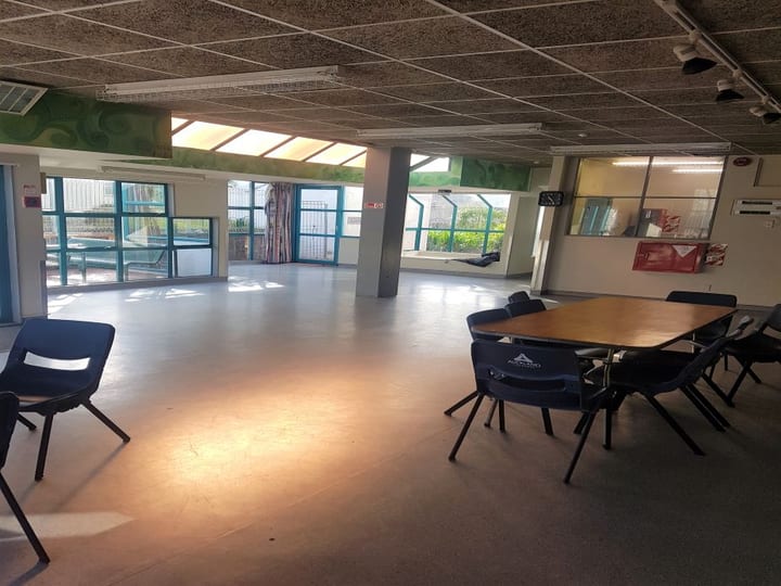 Open room with concrete ceiling, table and chairs, colourful mural on back wall