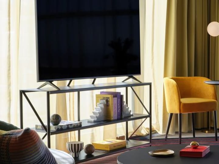 Yellow velvet chairs around a dark round table, large window with sheer curtains