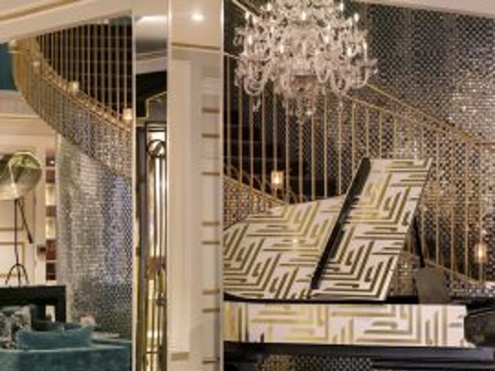 Ornate hotel lobby with gold staircase, chandelier and patterned walls