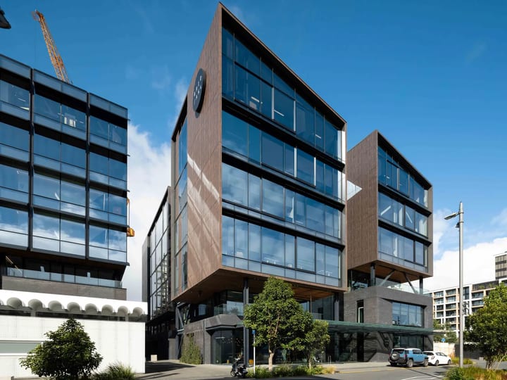 Multi-storey commercial building with timber and glass facade under blue sky
