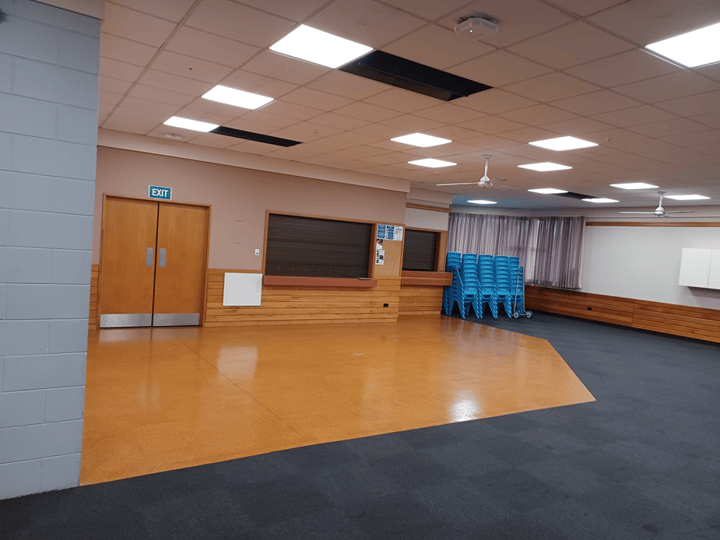 Empty hall with orange and dark carpet floor and stacked blue chairs