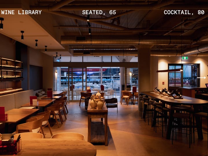 Industrial-style bar and dining room with wine shelves and text overlay showing capacity