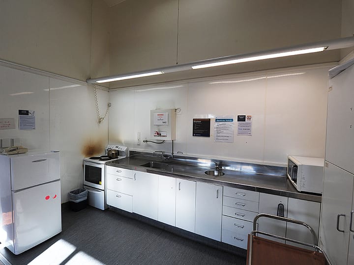 Plain community hall kitchen with stainless bench, fridge and microwave