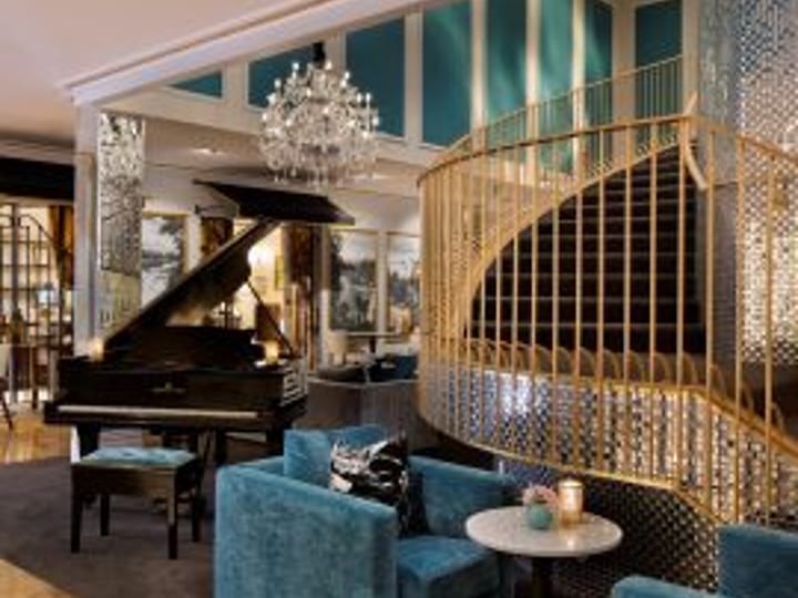 Luxury hotel lounge with grand piano, blue velvet sofas and gold staircase