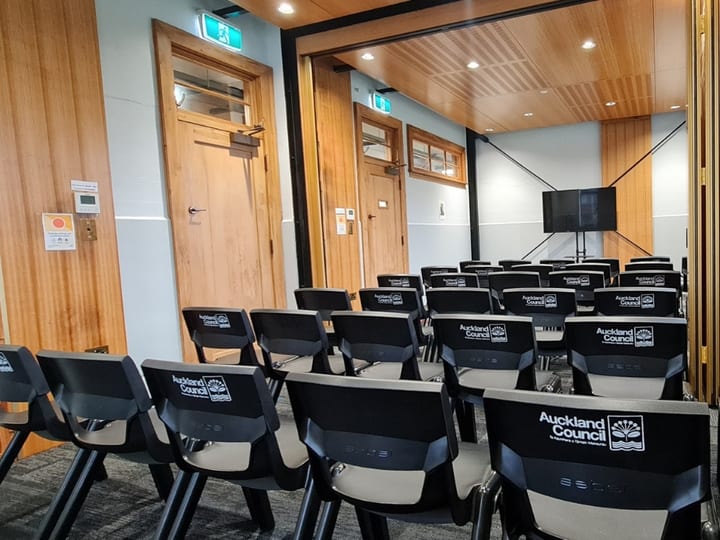 Room with chairs in rows facing a wall-mounted screen