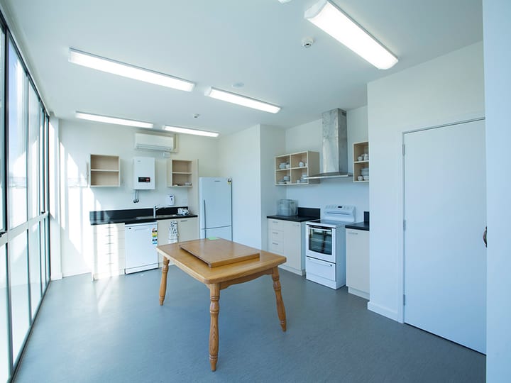 Kitchen with stove, fridge, overhead rangehood, and open shelving