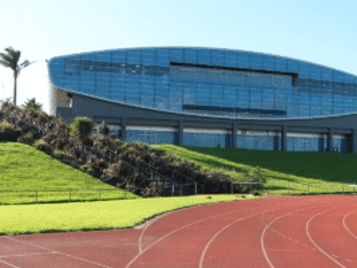 Modern glass arena building with running track in foreground