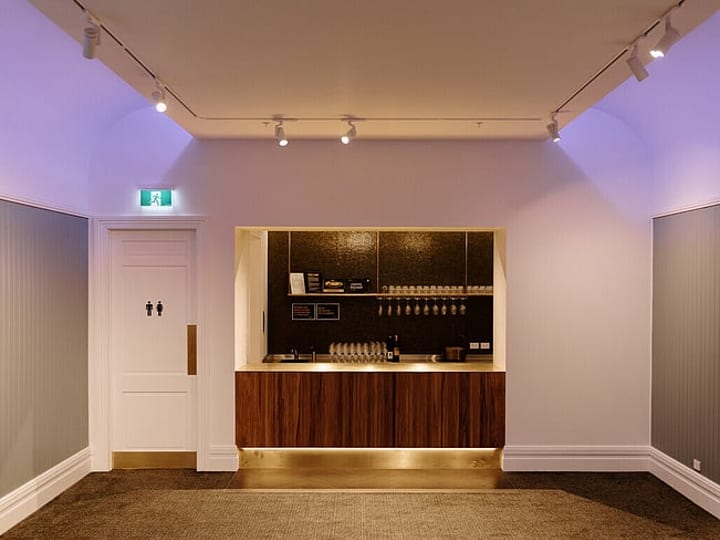 White-painted room with coloured uplighting and a built-in bar alcove with dark tiled splashback