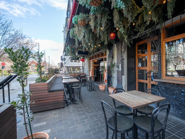 Restaurant facade with outdoor tables, hanging greenery, and timber-framed windows