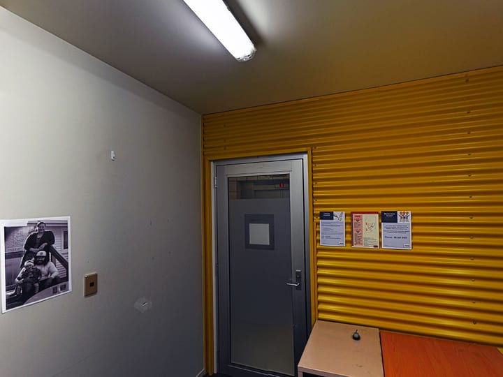 Small room with dark carpet, orange wall accent and stacked red chairs