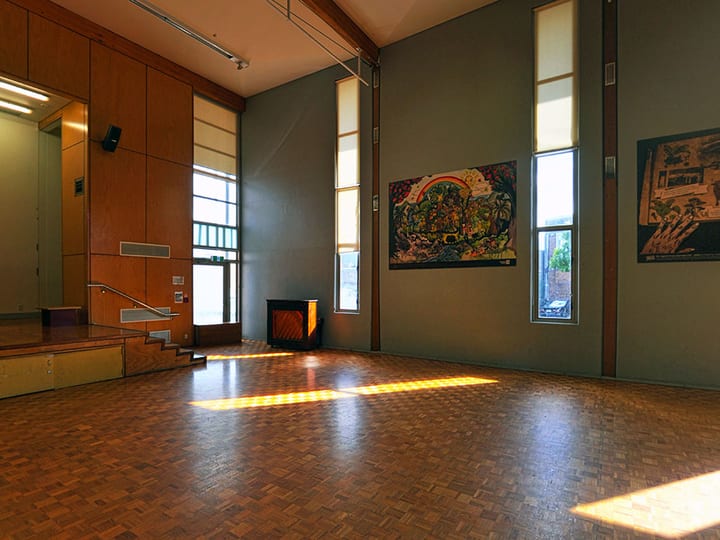 Hall interior with parquet floor, raised platform at one end and large windows