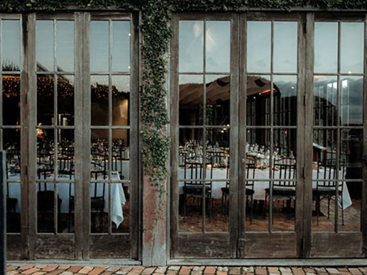 Restaurant dining room viewed through open glass doors with set tables