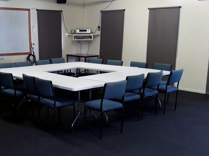 Meeting room with U-shaped table layout, whiteboard, and roller blinds
