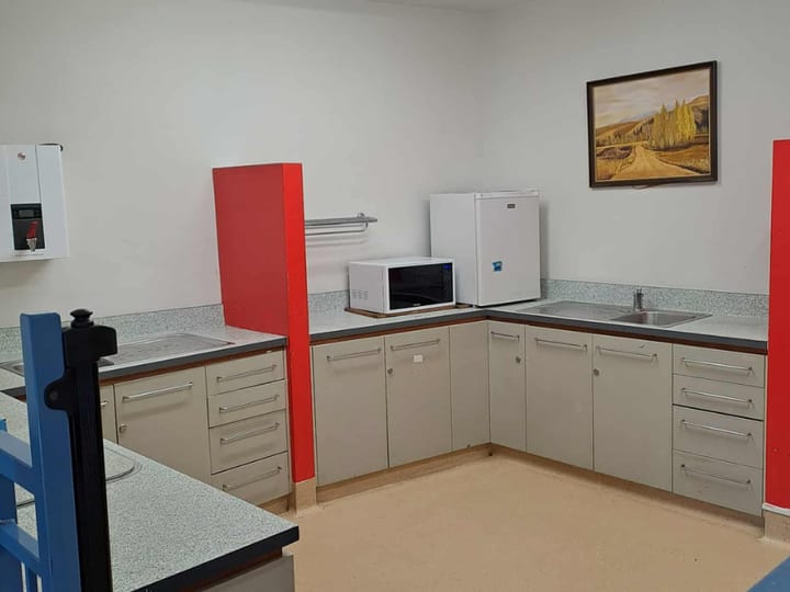 Compact kitchen with grey cabinetry, microwave, and small fridge