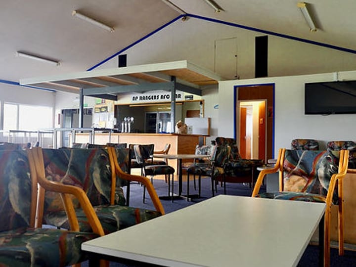 Clubroom interior with tables, chairs and bar counter visible in background