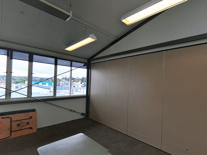 Small plain room with movable partition wall, carpeted floor and fluorescent lighting