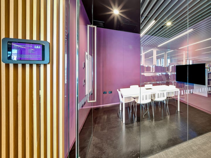 Glass-enclosed meeting room with purple feature wall and screen