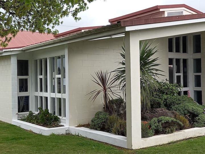 White rendered hall wing with textured block facade, red-tiled roof, and garden border