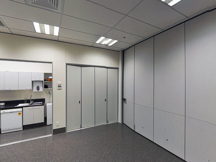 Empty meeting room with folding partition walls and kitchenette visible