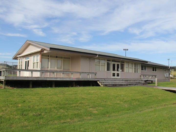 Side view of weatherboard lounge building with deck on green sports field