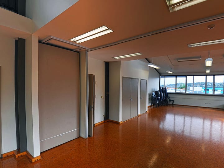 Large open hall with polished floor, movable partition walls, and windows overlooking water