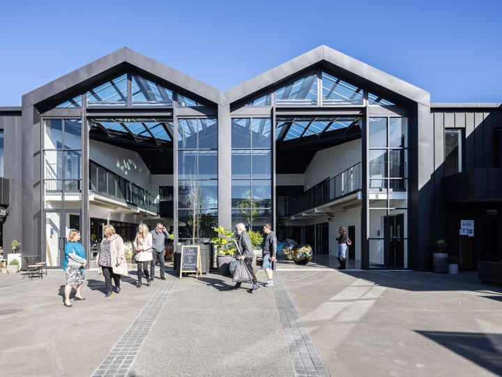 Venue courtyard in daylight with guests and gabled glazed building facade
