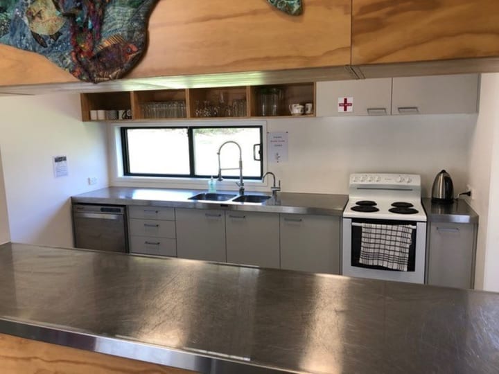 Small kitchen with stainless steel bench, oven, and open shelving above