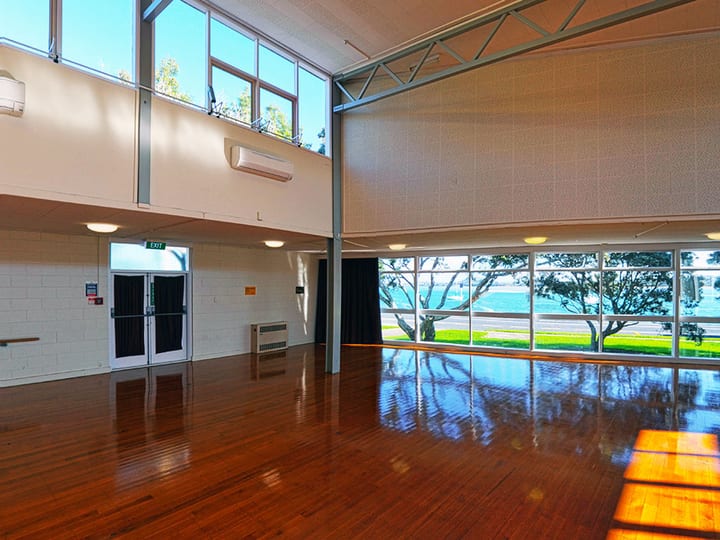Large open hall with polished wooden floor, high windows and bay view