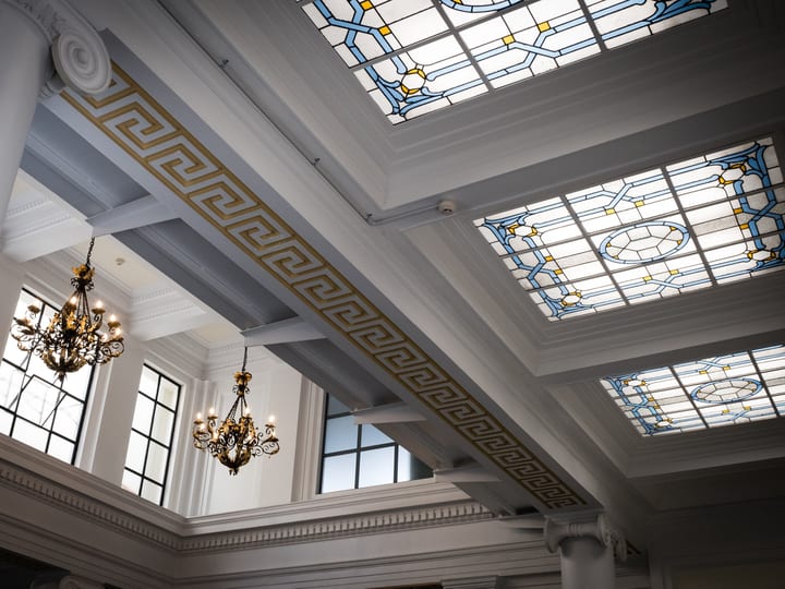 Grand hall interior with ornate stained-glass skylights, moulded cornices, and chandeliers