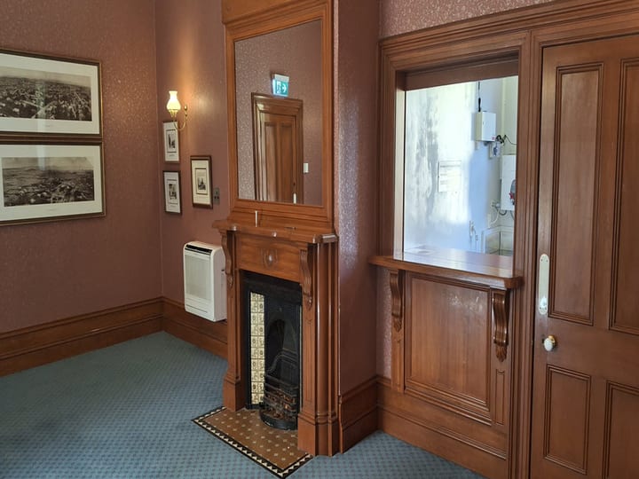 Victorian room with carved timber fireplace surround and framed artworks