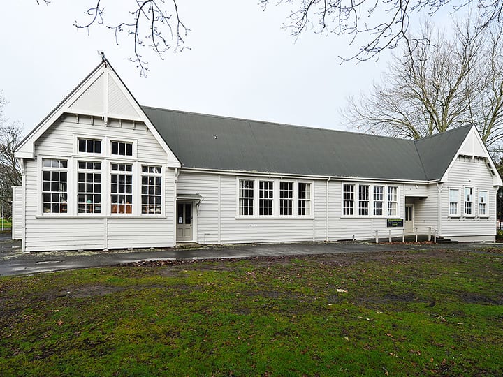 White weatherboard hall building with pitched roof and large windows